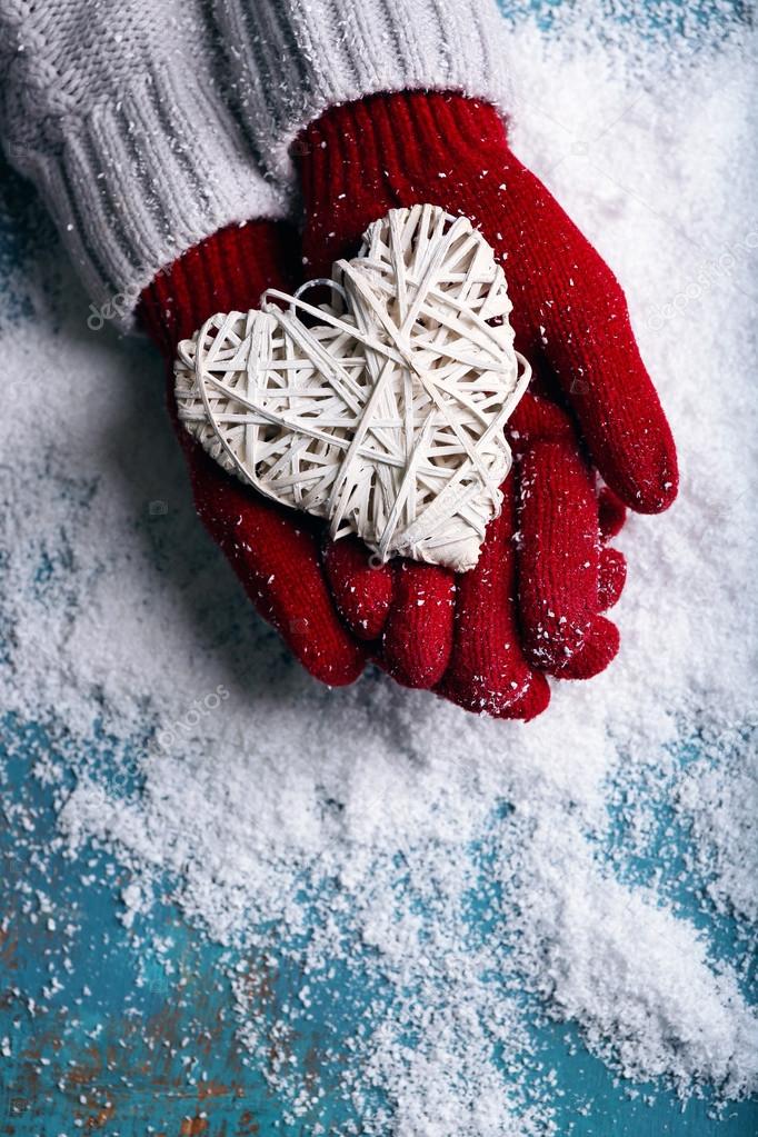 hands in mittens with decorative heart 