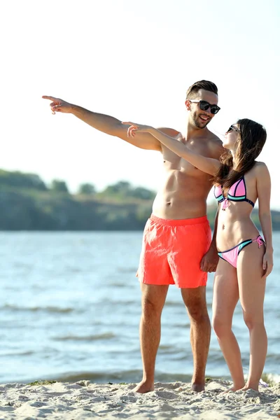 Casal feliz apontando para a praia — Fotografia de Stock