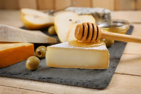 Different kinds of cheese with honey on wooden table — Stock Photo, Image