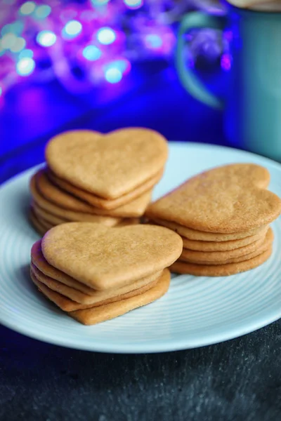 Biscotti a forma di cuore su piatto e tazza su un tavolo — Foto Stock