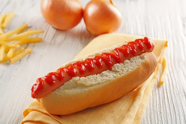 Hot dog hagymával, sült burgonyával, fából készült háttér — Stock Fotó