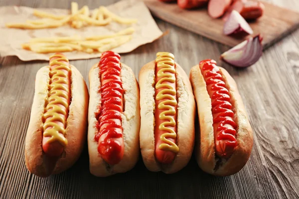 Perros calientes con patatas fritas y salchichas sobre fondo de madera —  Fotos de Stock