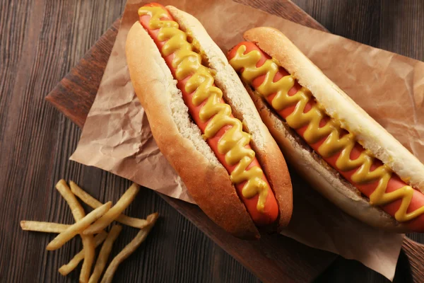 Hot dog con cipolle e patate fritte su sfondo di legno — Foto Stock