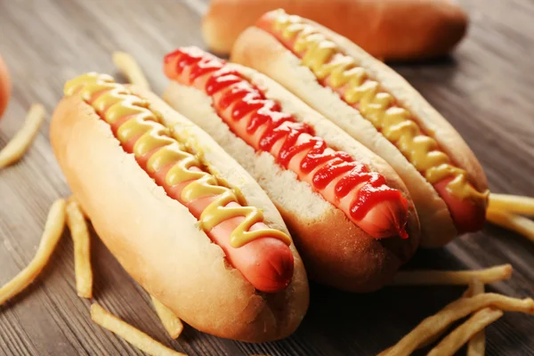 Cachorros-quentes com batatas fritas no fundo de madeira — Fotografia de Stock