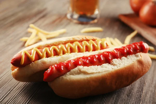 Hot dog, sült burgonyával és hagymával, fából készült háttér — Stock Fotó