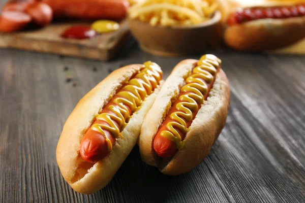 Cachorros-quentes com batatas fritas e salsichas frescas em fundo de madeira — Fotografia de Stock