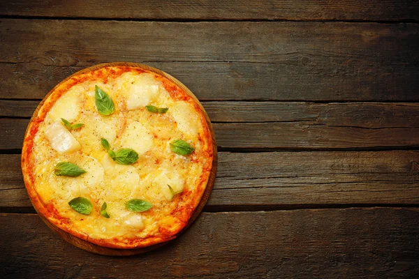 Smaczne pizze ozdobione bazylią na drewniane tła — Zdjęcie stockowe