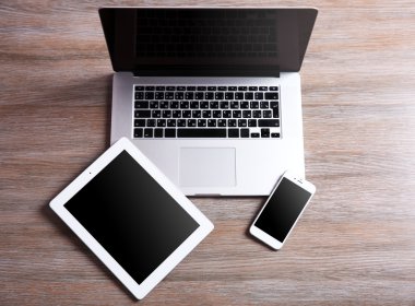Modern dizüstü bilgisayar, akıllı telefon ve tablet ahşap bir masa üzerinde