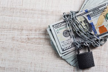 Kilit ve zincir ahşap masa arka plan üzerinde dolar para birimi