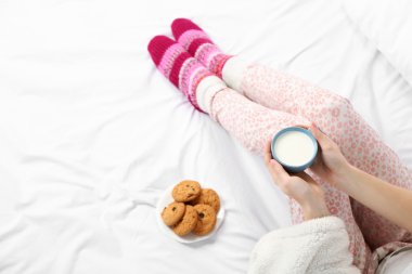 Kadın onun yatağında süt fincan tutan pijama