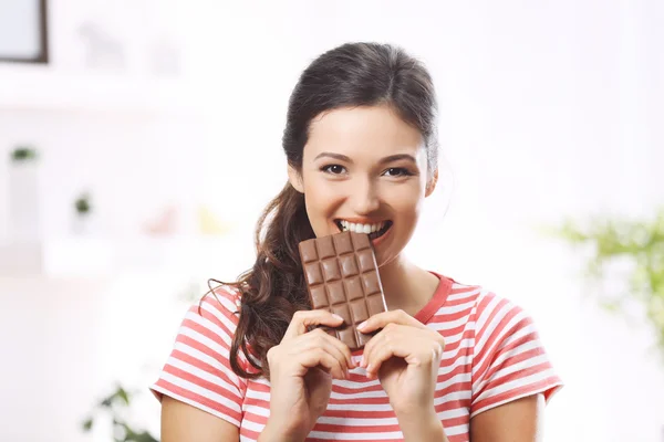 Portrét krásná mladá brunetka s čokoládou v místnosti, zblízka — Stock fotografie