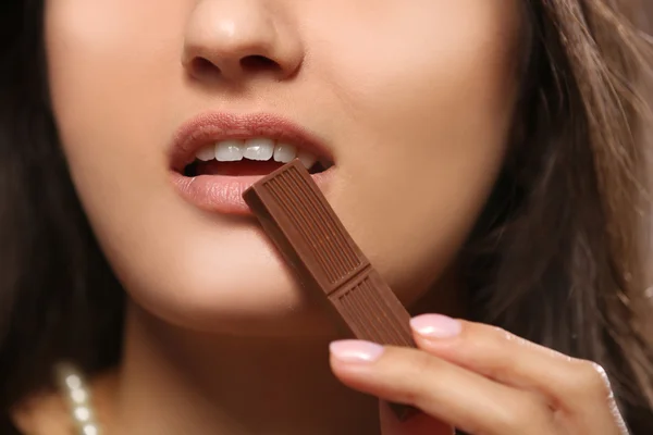Loving chocolate woman bites bar to enjoy the taste, close up — Stock Photo, Image