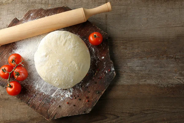 Свежее тесто с помидорами на деревянной доске, крупным планом — стоковое фото