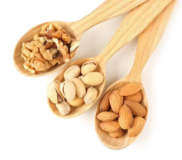 Cucharas de madera con nueces, pistachos y almendras, aisladas sobre blanco —  Fotos de Stock