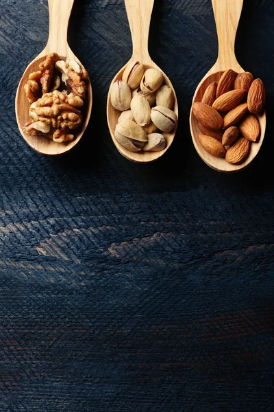 Κουτάλια με καρύδια, φιστίκια και αμύγδαλα, σε γκρι φόντο ξύλινη — Φωτογραφία Αρχείου