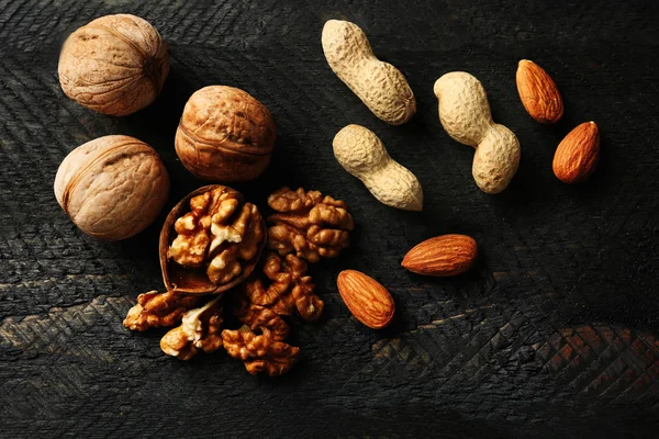 Mandle, oříšky a vlašské ořechy na šedém pozadí dřevěná — Stock fotografie