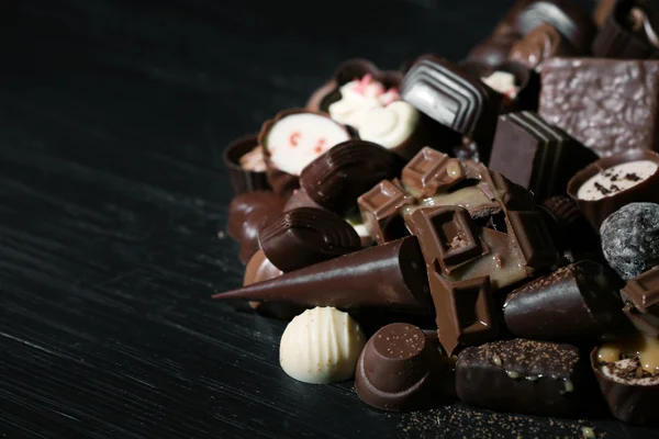 Auswahl an leckeren Schokoladenbonbons und Zimt auf Holztischhintergrund — Stockfoto