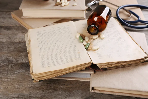 Libros, píldoras y estetoscopio en primer plano de mesa de madera —  Fotos de Stock