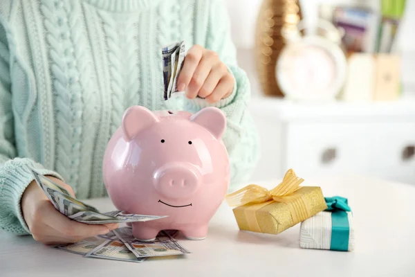 Vrouw dollar biljetten ingebruikneming piggy bank. — Stockfoto