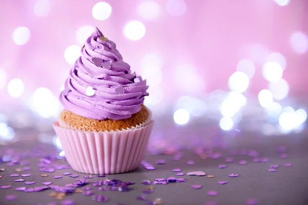 Cupcake com cobertura de creme roxo em um fundo de brilho, close-up — Fotografia de Stock