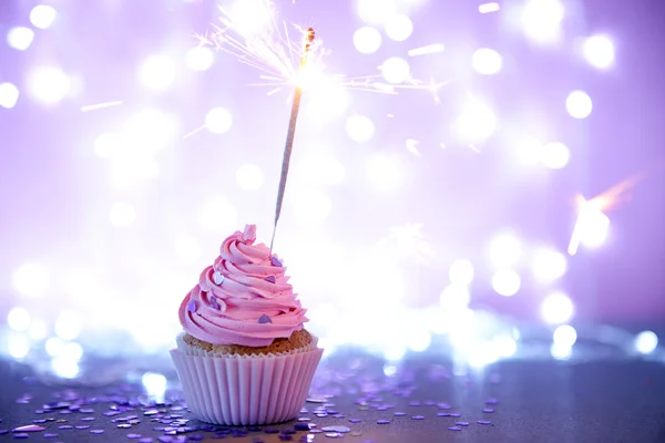 Cupcake con glaseado de crema rosa y brillo sobre un fondo brillante —  Fotos de Stock