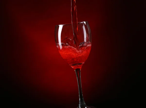 Vin hälla i glas på mörk röd bakgrund — Stockfoto