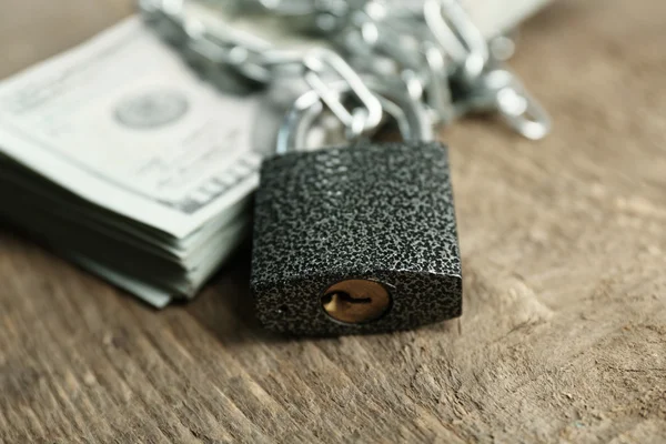 Dolar mata uang dengan kunci dan rantai pada latar belakang kayu — Stok Foto
