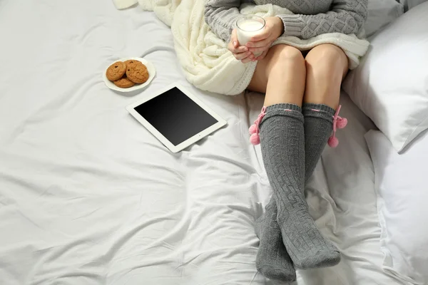 Frau mit Tablette trinkt Milch auf ihrem Bett — Stockfoto