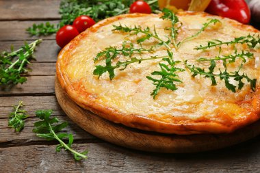 Lezzetli pizza ahşap arka plan üzerinde sebze ve otlar ile dekore edilmiş, yakın çekim