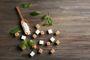 Sugar cubes and stevia  on wooden background clipart