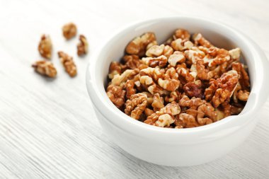 Beyaz ahşap zemin üzerinde kapta ceviz taneleri