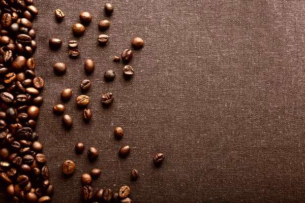 Grãos de café torrados sobre fundo têxtil cinzento — Fotografia de Stock