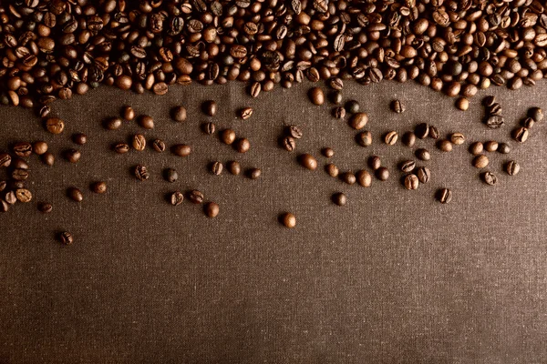 Graines de café torréfiées sur fond textile gris — Photo