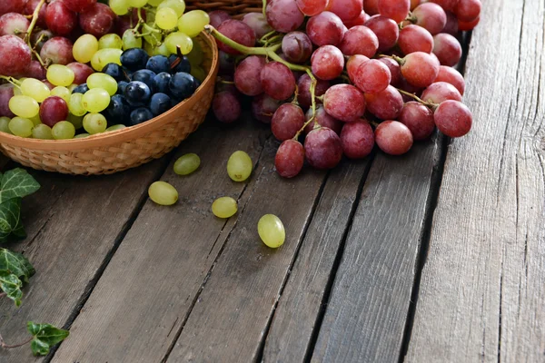 Uva en cesta sobre mesa de madera — Foto de Stock