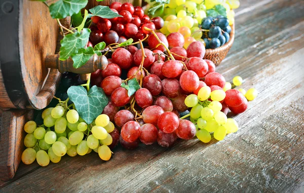 Grapes in bowl and barrel on wooden table — Stock Photo, Image