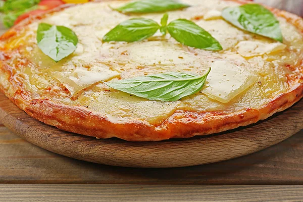 Sabrosa pizza decorada con albahaca y verduras sobre fondo de madera, de cerca — Foto de Stock