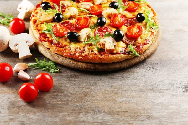 Delicious tasty pizza with ingredients on wooden table — Stock Photo, Image