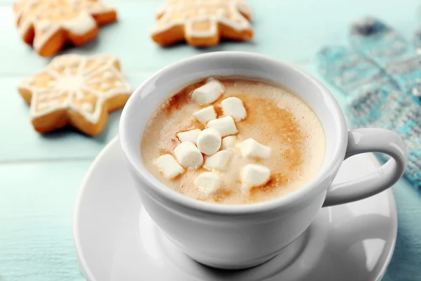 Чашка горячего какао с зефиром, печеньем и теплыми перчатками на голубом столе — стоковое фото