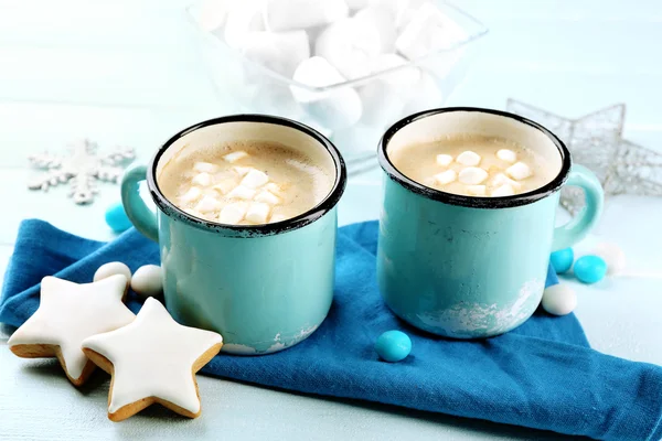 Dos tazas de cacao caliente con malvavisco, galletas y servilleta en la mesa azul —  Fotos de Stock