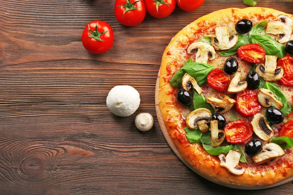 Deliziosa gustosa pizza con ingredienti sul tavolo di legno — Foto Stock