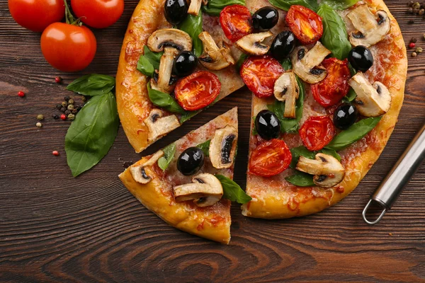 In Scheiben geschnitten leckere Pizza mit Gemüse auf Holztisch — Stockfoto