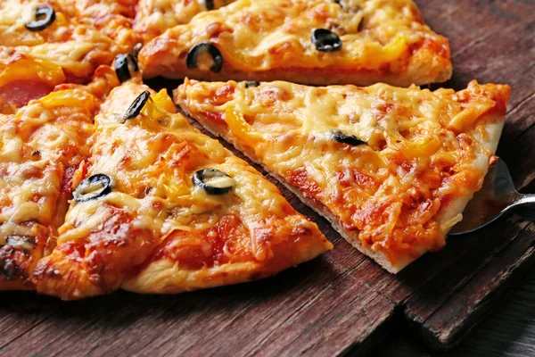 Pyszne plasterki pizzy na pokładzie drewnianym, z bliska — Zdjęcie stockowe