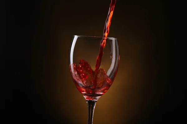 Wine pouring in glass on brown background — Stock Photo, Image