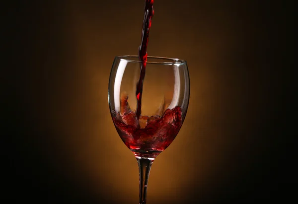 Wine pouring in glass on brown background — Stock Photo, Image
