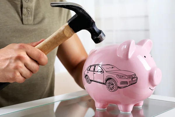 Man with hammer going to break piggy bank