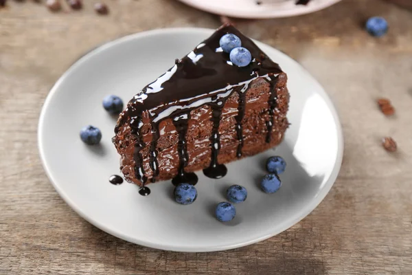 Schokoladenkuchen mit Schokoladencreme und frischen Blaubeeren auf Teller, auf Holzgrund — Stockfoto