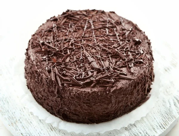 Tasty chocolate cake on wooden table, on light background — Stock Photo, Image