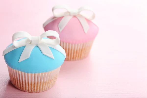 Tasty cupcakes with bow on color wooden background — Stock Photo, Image