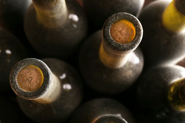 Stacks of dusty wine bottles on wooden background, upside view. Close up — Stock Photo, Image