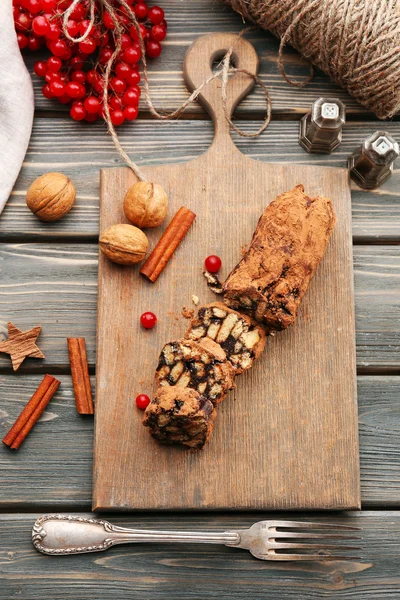 Salame de chocolate em uma tábua de cortar sobre fundo de madeira — Fotografia de Stock